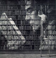 a man standing on top of a ladder in front of a book shelf filled with books