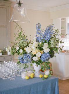 a vase filled with blue and white flowers sitting on top of a table next to wine glasses