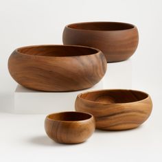 three wooden bowls sitting next to each other on a white surface with one bowl in the middle