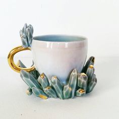 a coffee cup sitting on top of a saucer next to a golden ring and flowers