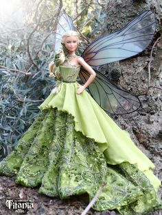a green fairy doll standing next to a tree
