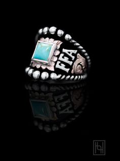 a silver and turquoise stone ring on a black background