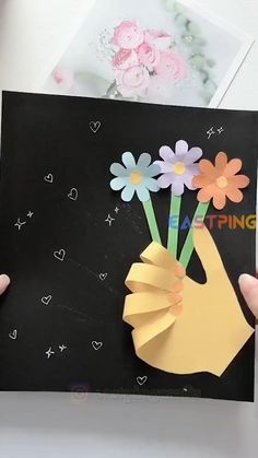 someone is holding up a card with flowers in it