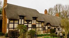 an old house with thatched roof and chimneys
