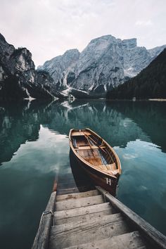 a small boat sitting on top of a body of water next to a mountain range