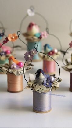 several spools of thread are sitting on top of each other, with tiny birds perched on them