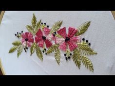 a close up of a piece of embroidery on a white cloth with green and pink flowers