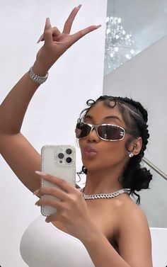 a woman wearing sunglasses taking a selfie with her cell phone in front of the camera