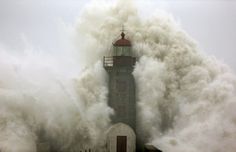 a lighthouse surrounded by huge waves in the ocean