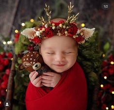 a baby wearing a christmas wreath and holding a stuffed animal