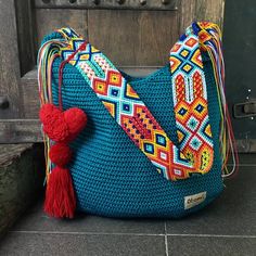 a crocheted bag with a red heart hanging from it's handle and tassel