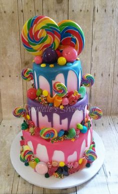 a multi layer cake with candy and lollipops on top is shown in the instagram