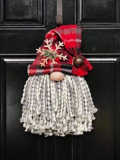 a door hanger with a christmas decoration on it's face and scarf hanging from the front