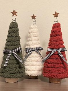 three knitted christmas trees in different colors and sizes, tied with bows on top