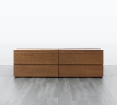 a wooden dresser sitting on top of a hard wood floor next to a white wall