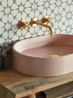 a pink sink sitting on top of a wooden counter next to a potted plant