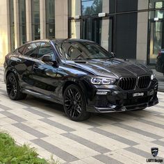 a black bmw suv parked in front of a building on a checkerboard sidewalk