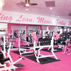 a gym with pink carpeting and white exercise equipment in the center is full of weight machines