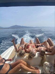 four women are lounging on the back of a boat