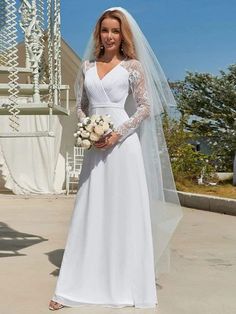 a woman in a white wedding gown and veil posing for the camera with her bouquet