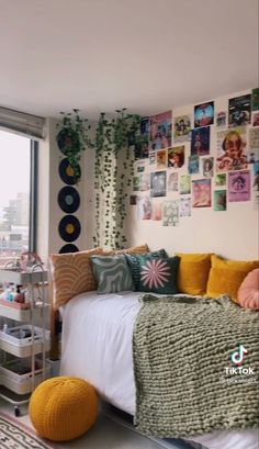 a bedroom with lots of pictures on the wall and a bed in front of a window