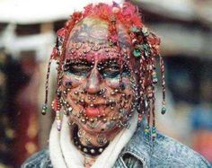 a man with his face covered in beads and piercings, wearing a denim jacket