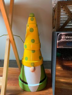 a yellow and green toy sitting on top of a wooden floor next to a sign