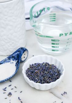 lavender sprigs in a white bowl next to a measuring cup and spoon on a counter