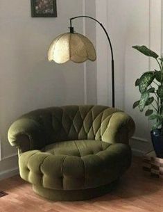 a green chair sitting on top of a hard wood floor next to a potted plant