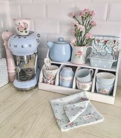 a dollhouse kitchen with pink flowers and blue dishes on the counter, including a coffee maker