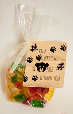 a bag filled with gummy bears sitting on top of a white table next to a sign