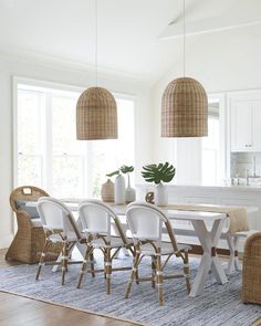 a dining room table and chairs with wicker lamps hanging from the ceiling above it