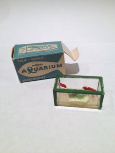 an open box of aquarium next to it's cardboard packaging on a white surface