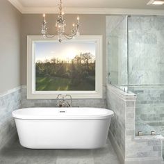 a white bath tub sitting in a bathroom next to a walk in shower and a chandelier