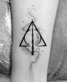a harry potter symbol tattoo on the right leg, with water droplets around it and an ink splattered background