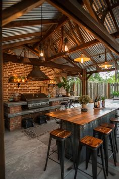 an outdoor kitchen with wooden tables and stools next to the bbq grill area