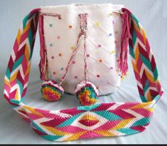 a crocheted bag with two pom poms hanging from it's side