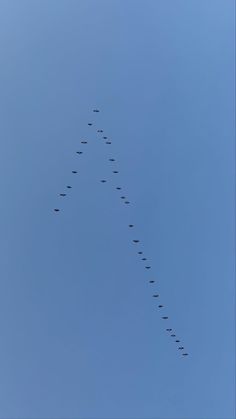 a long line of airplanes flying in the sky together, leaving a trail behind them