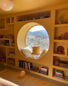 there is a round window in the wall above bookshelves and a bed with pillows on it