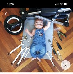 a baby is laying on the floor surrounded by tools