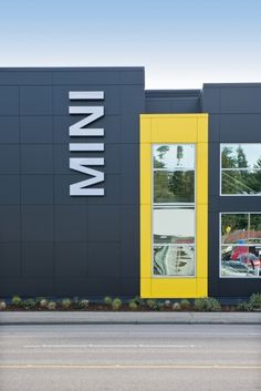 the front of a building that is painted yellow and gray with windows on each side