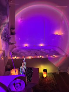 a bath tub filled with water next to a laptop computer and candles in front of it