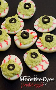 decorated devil eye cookies with green frosting and sprinkles on black surface