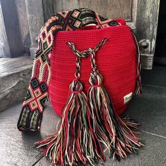 a red purse with tassels on the handles