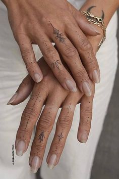 two people with tattoos on their hands holding each other's fingers and wearing rings