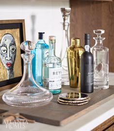an assortment of liquor bottles on a counter top with a framed painting in the background
