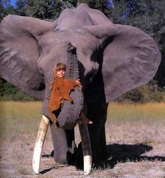 a woman standing next to an elephant with tusks on it's back