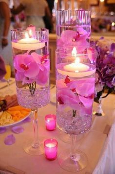 two vases filled with flowers and candles on top of a table