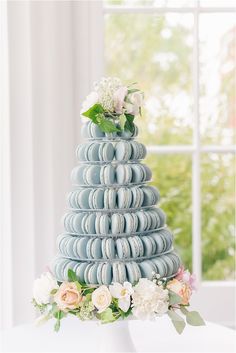 a wedding cake made out of macaroni shells and flowers on a table in front of a window