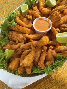 a platter filled with fried chicken and lettuce next to a dipping sauce
